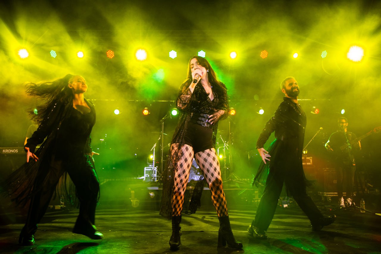 Olive Shows Madonna tribute - the soloist and two dancers mid-move in black lace and checkered tights under yellow and green light