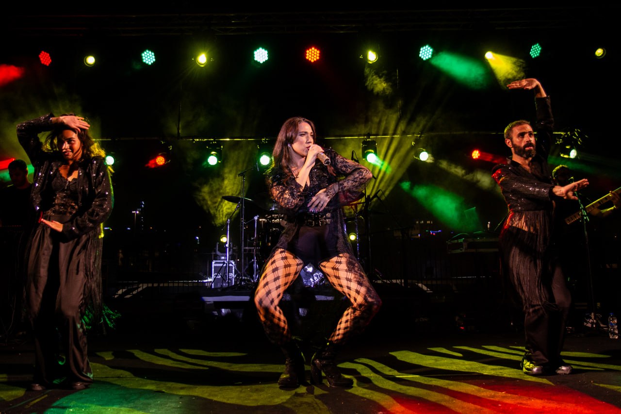 Olive Shows Madonna tribute - the soloist in a low dance pose flanked by two dancers under green and red light